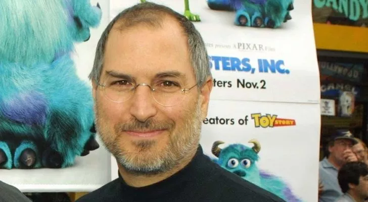 Стив Джобс с плакатом Pixar за спиной