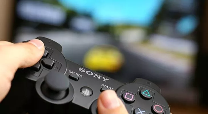 Человек, играющий в игру, держит контроллер PS3.