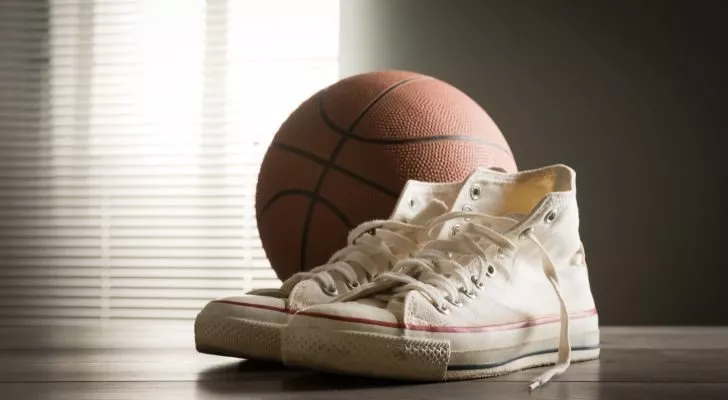 Белые туфли Converse с низким вырезом лежат рядом с баскетбольным мячом