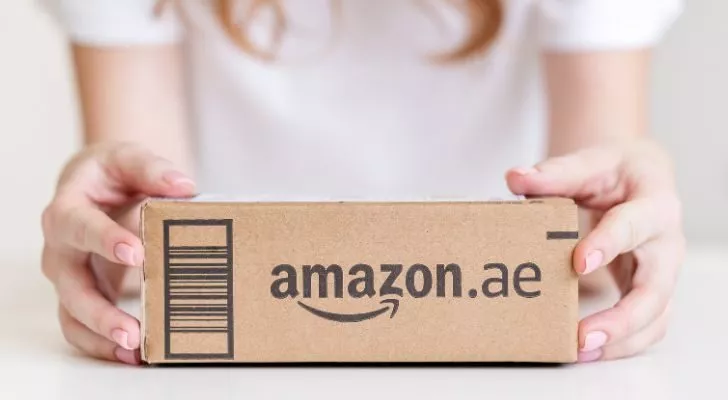Женщина держит коробку, в которой есть "Amazon.ae" напечатан сбоку