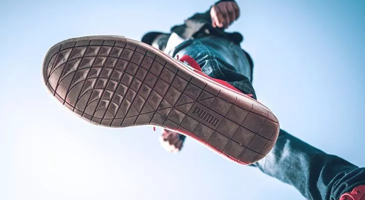 Мужчина в туфлях Puma, вид снизу. Обувь Puma имеет логотип бренда на подошве.